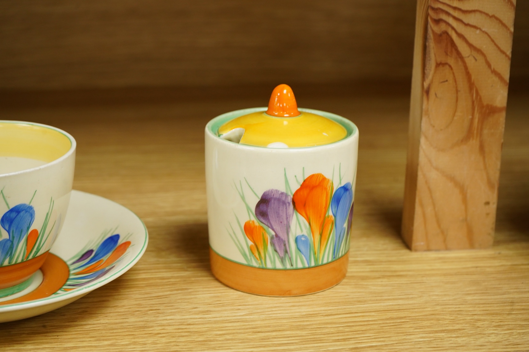 A Clarice Cliff ‘crocus’ pattern preserve jar and cover, 10cm high and a similar cup and saucer